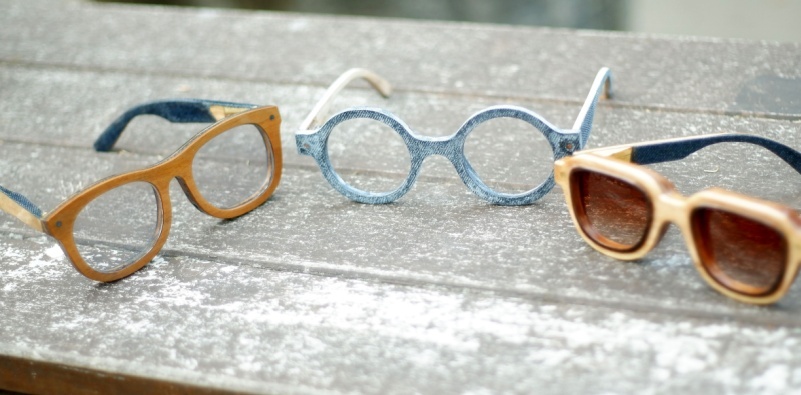 Three pairs of wooden eyeglasses on a wooden bench