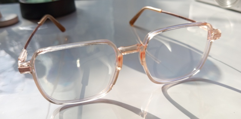A pair of pink colored transparent glasses frames on a glass table top