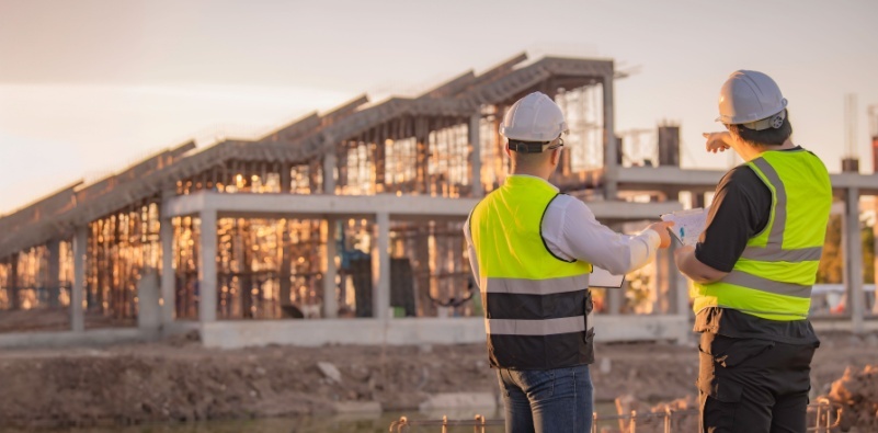 Image of two construction workers looking at a building.