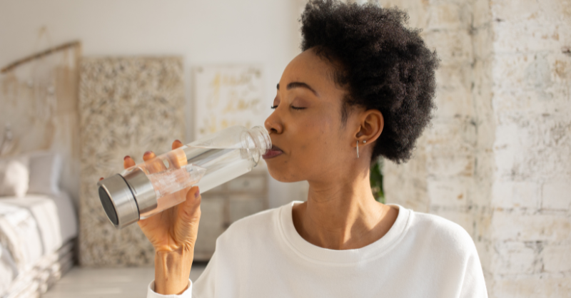 A woman drinking from a clear water bottle.