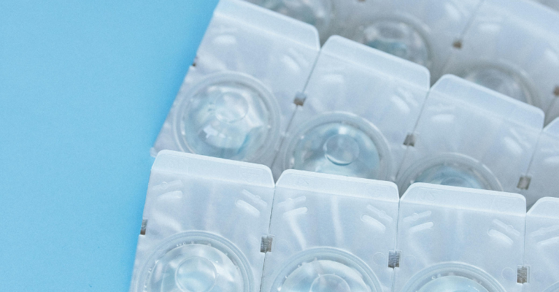 Strips of daily contact lens blister packs on a blue background.